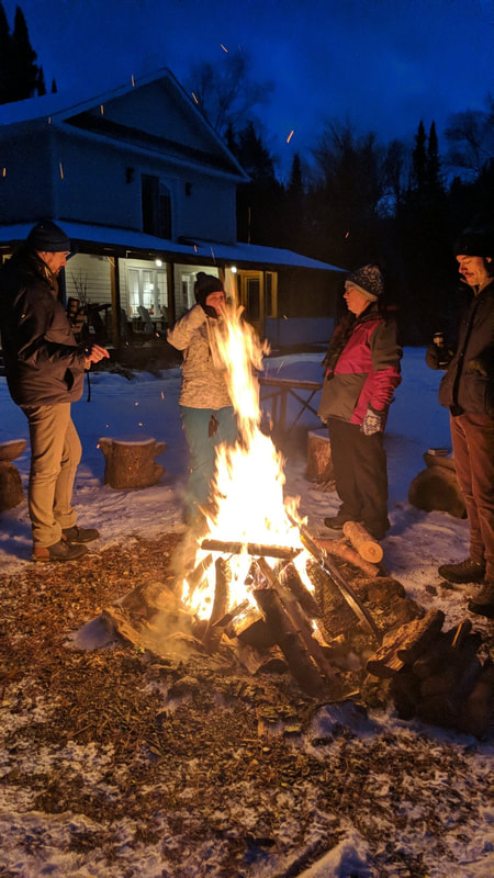 Students warm up around an evening bonfire