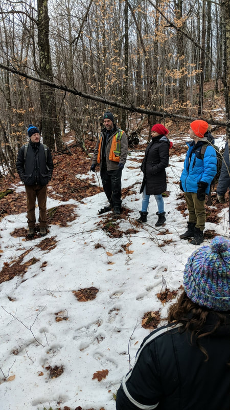 Students listen to presentations out in the snowy forest